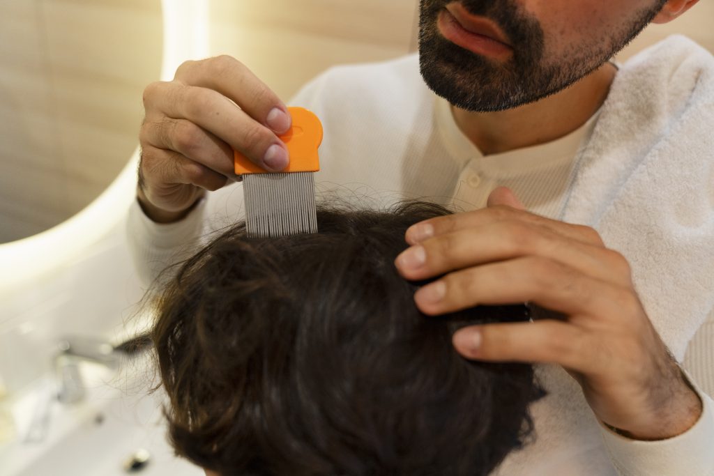 Father using a lice comb to inspect and care for hair while demonstrating proper hair care tips for patches and wigs maintenance